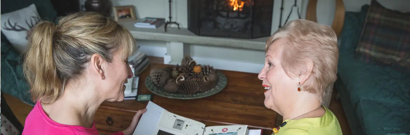 dementia care options_carer and patient reading in front of fireplace